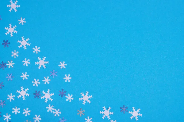 Snowflake confetti on light blue background. — Stock Photo, Image