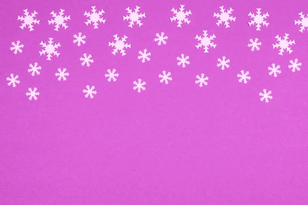 冬のお祭りの気分を作成する薄紫の背景に白の大小のスノーフレーク紙吹雪 クリスマスと新年のお祝いのコンセプト — ストック写真