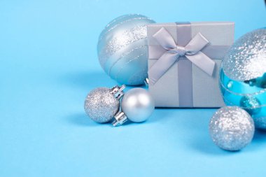 Güzel gümüş hediye kutusu parlak Noel baubles kopya alanı pastel mavi zemin üzerine ve sevimli ipeksi yayla bileşimi. Noel ve yeni yıl kutlama kavramı.