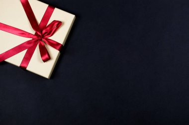 Hediye kutusu ile siyah zemin üzerine kırmızı ipek kurdele ile bağlanmış. Tatil ve mevsimlik satış konsepti.
