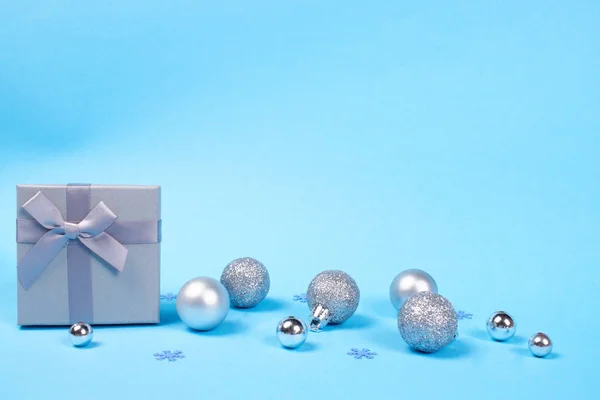 美丽的礼品盒的组成与可爱的丝质弓和闪亮的圣诞小泡蓝色柔和的背景装饰与雪花五彩纸屑与复制空间 — 图库照片