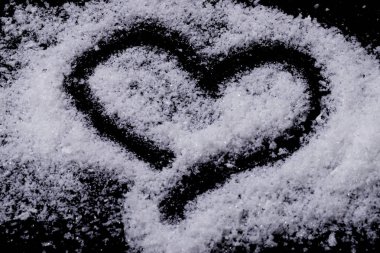 Kar örtüsü siyah bir zemin üzerine çizilmiş kalp. Kış konsepti Merhaba.