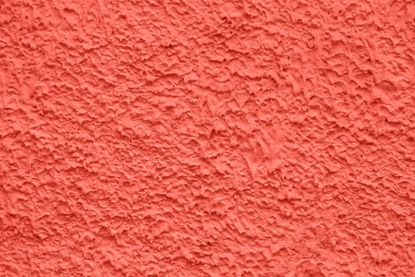Relief of decorative wall plastering colored in coral which is the main trend of the year 2019. Structured texture for a background.