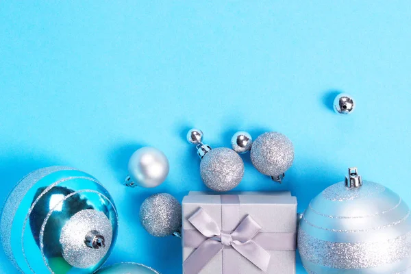 美丽的银色礼品盒的组成与可爱的丝质弓和大小闪亮的圣诞小泡蓝色柔和的背景与复制空间 新年和圣诞节庆祝概念 — 图库照片
