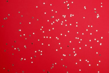 Yıldız şeklinde altın konfeti canlı kırmızı zemin üzerine. Şenlikli ve kutlama kavramı.