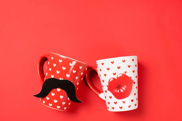 Couple of red cup with mustache and white cup with lips painted with hearts on vibrant background. Valentines day romantic dating concept. Mr and Mrs mugs concept with copy space for text.