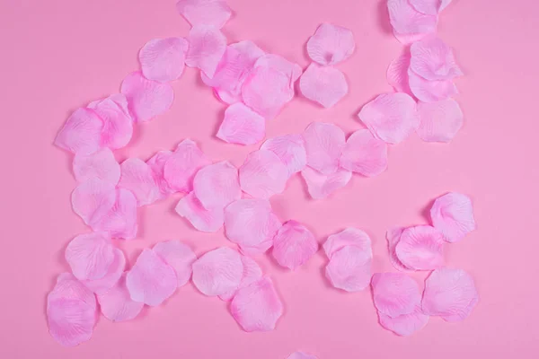 Artificial tender and delicate pink rose petals on the background of the same tone.