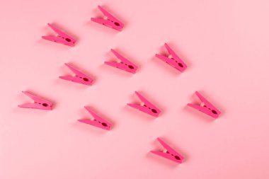 Pembe arka plan üzerinde kırmızı plastik clothespins bir demet.