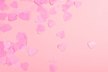 Pastel pembe arka plan kopya alanı için metin ile aynı renkteki dağınık kalp şeklinde konfeti ile. Sevgililer günü kavramı. Sembolleri seviyorum. Festival zemin.
