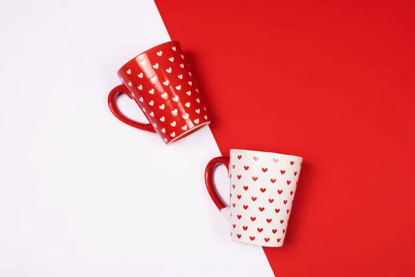 Beautiful and cute mugs decorated with cute little hearts pattern on vibrant double-colored high contrast background. Love, couple and Valentine\'s Day concept.