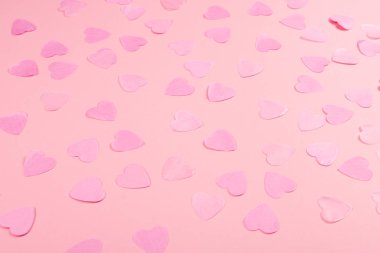 Pastel pembe arka plan kopya alanı için metin ile aynı renkteki dağınık kalp şeklinde konfeti ile. Sevgililer günü kavramı. Sembolleri seviyorum. Festival zemin.
