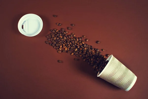 Taza de café con granos de café caídos en una mesa . — Foto de Stock