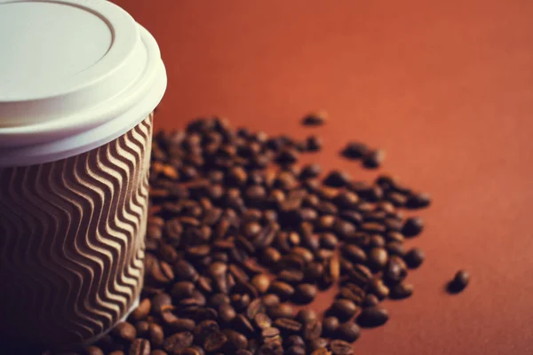 Papel taza de café y frijoles sobre fondo marrón . — Foto de Stock