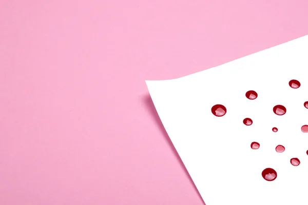 Livro branco com gotas vermelhas sobre fundo rosa . — Fotografia de Stock