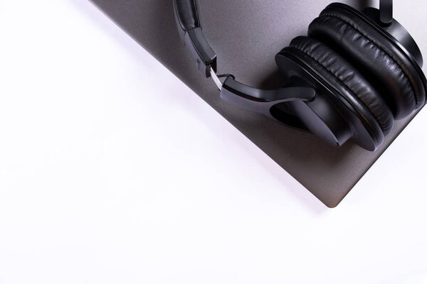 Silver laptop and black headphones isolated on white working background with copy space for text. Work day, daily routine and music listening concept.