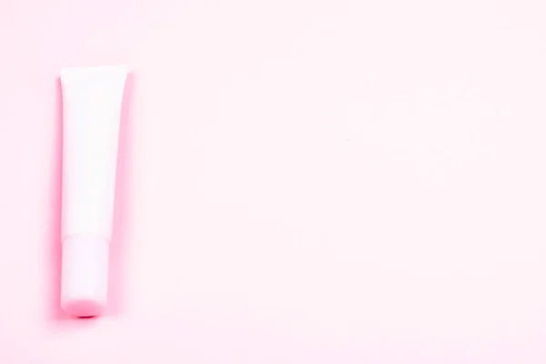 Rosa kosmetiska röret på bakgrund av samma ton. — Stockfoto