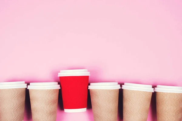 Papír csészék rózsaszín háttérrel — Stock Fotó