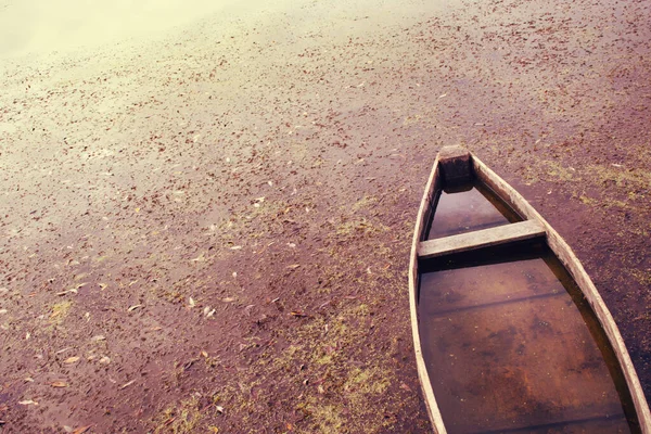 Velho barco de madeira em um rio água suja . — Fotografia de Stock