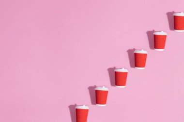 Pembe arkaplanda kağıt bardakların deseni.