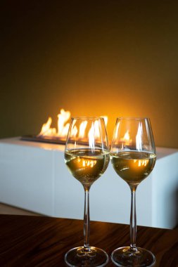 İki kadeh beyaz şarap ile yeşil şişe şömine kopya alanı ile yakın