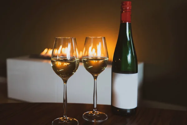 İki kadeh beyaz şarap ile yeşil şişe şömine kopya alanı ile yakın