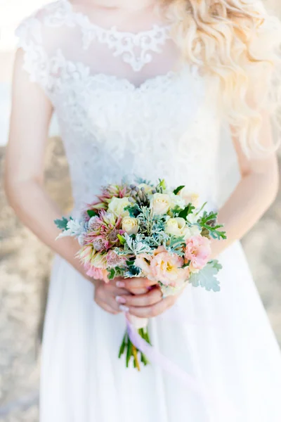 A wedding bouquet in the hand. A bouquet of flowers as a symbol of love is held by a couple in love during the wedding. Light gentle style