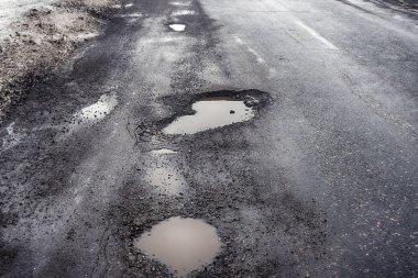 Eski yolu. Büyük çukurlar ve çukurların bulutlu hava, kalın karanlık bulutlar gökyüzünde kavramı karayolu. Zor yoldan, seçim sembolü