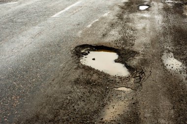 yol çukurları ve kar üzerinden su birikintileri çatlaklar ile kaplıdır. Yatay gri bulutlu havalarda kış yolun. Yol onarım kavramı, arabanın sürücüsü için opaklık