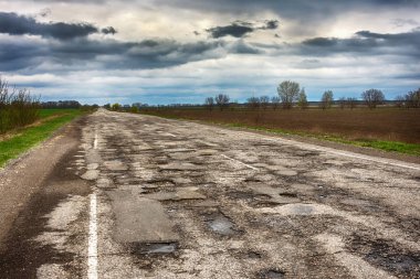 Eski yolu. Büyük çukurlar ve çukurların bulutlu hava, kalın karanlık bulutlar gökyüzünde kavramı karayolu. Zor yoldan, seçim sembolü