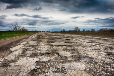 Eski yolu. Büyük çukurlar ve çukurların bulutlu hava, kalın karanlık bulutlar gökyüzünde kavramı karayolu. Zor yoldan, seçim sembolü