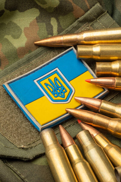 боевые пули на фоне украинского флага. Камуфляжный символ украинской армии
