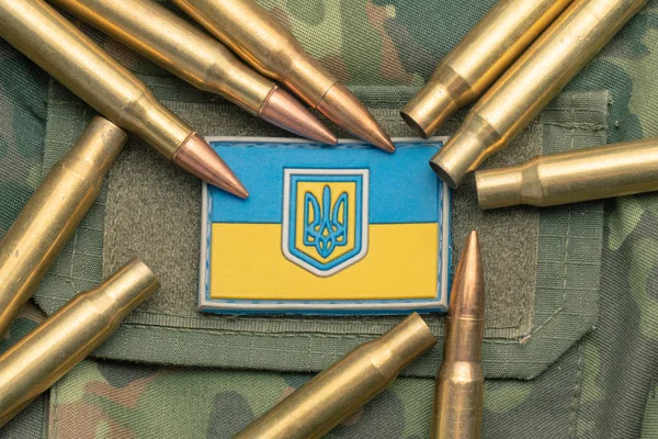 Ukrainian flag and coat of arms against camouflage and battle bullets. The concept of the Ukrainian defense army, highlight