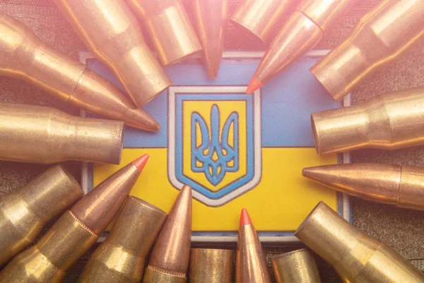 Ukrainian flag and coat of arms against camouflage and battle bullets. The concept of the Ukrainian defense army, highlight