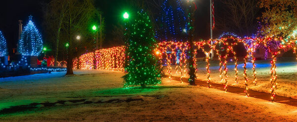 A village square festively lit up for Christmas, featureing a tunnel of lighted arches