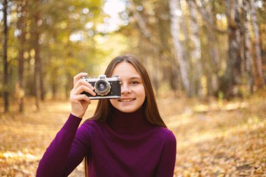 Sevimli Genç kız ile vintage fotoğraf makinesi. Sonbahar ormandaki retro bir kamera ile kız portresi.