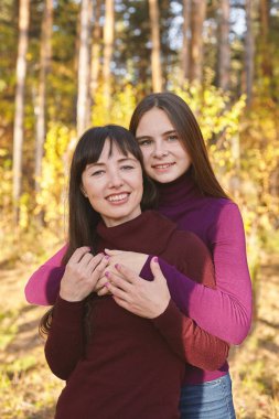 Anne ve kızı sonbahar ormandaki portresi. Güzel genç kadın ve genç sonbahar park.