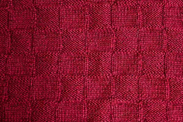 Texture of warm red knitted winter clothes. Background knitted cozy clothes handmade