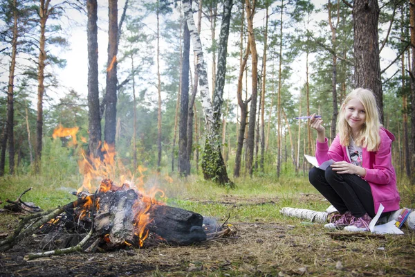 在夏日的午后 在炉火旁 一个快乐的小女孩坐在原木上 — 图库照片