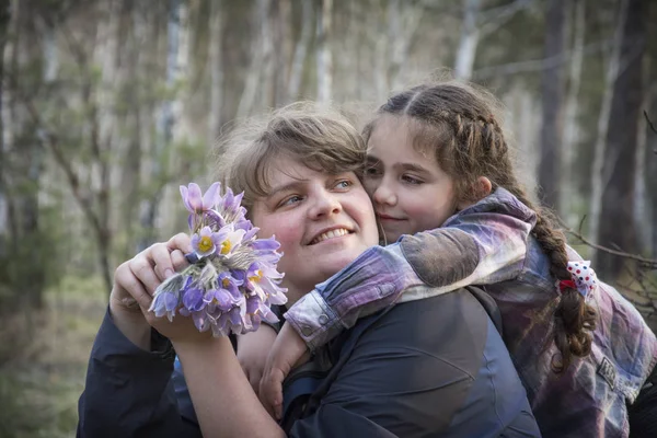 In the spring in the forest, a little girl hugs her mother and g — Stock Photo, Image