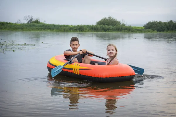 In estate sul fiume ragazzo felice con una ragazza nuotare in un rubbe — Foto Stock