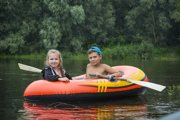 En été sur la rivière garçon heureux avec une fille nager dans un rubbe — Photo