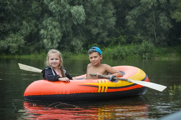 In the summer on the river happy boy with a girl swim in a rubbe — Stock Photo, Image