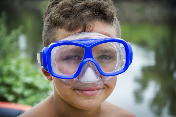 In the summer, a boy in a diving mask stands on the bank of the — Stock Photo, Image