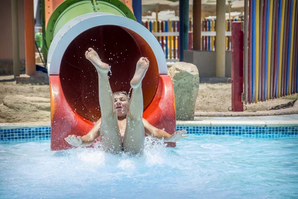 No verão, um dia ensolarado brilhante no parque aquático, o menino desliza — Fotografia de Stock