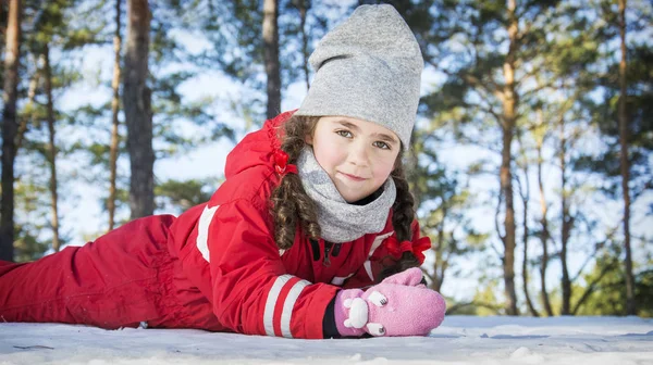 Im Winter, an einem sonnigen Tag im Wald, liegt ein kleines Mädchen — Stockfoto