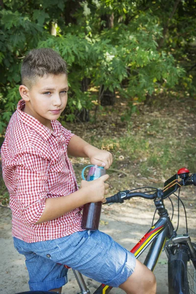 Pada musim panas, di hutan, anak itu minum air dari botol — Stok Foto