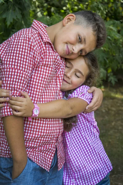 In the autumn forest, a small curly sister lovingly embraces her — Stock Photo, Image