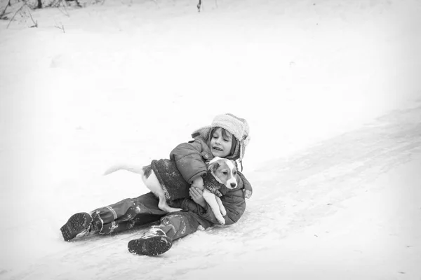 En invierno, en el hielo, un niño con un perro en sus brazos se deslizan por la h —  Fotos de Stock