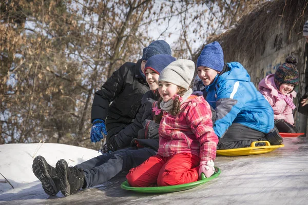 Im Winter, an einem strahlend sonnigen Tag, rutscht eine Schar von Kindern — Stockfoto