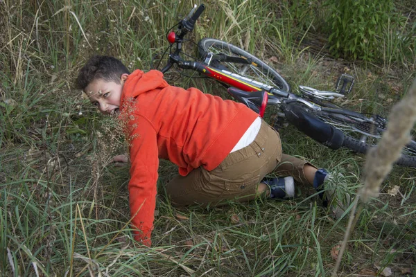 夏天，在森林里，男孩从自行车上摔到了地上 — 图库照片